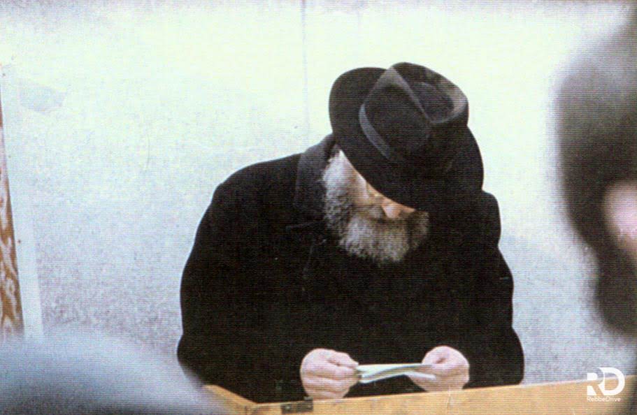 The Rebbe reading a note at a farbrengen, 10 Iyar 5724 (April 1964)
